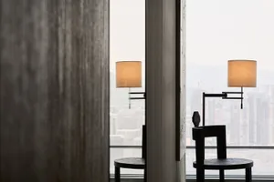 Modern minimalist office space featuring black wooden furniture and white lighting, with a view of a cityscape.