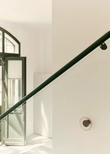 A modern, minimalist architectural design featuring a spiral staircase in a corner with natural light streaming in through a 