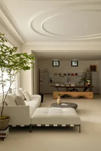 A minimalist living room featuring a white leather sofa and a round wooden coffee table.
