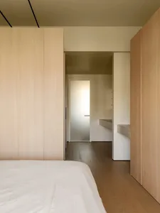 Modern bedroom with wood paneled walls and a white bed.
