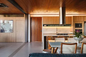A modern kitchen with wooden cabinets and a glass table.