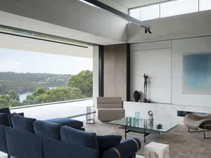 Modern living room featuring glass and concrete materials with a view of the natural landscape.