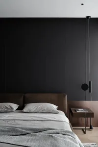 Modern minimalist bedroom with a textured fabric headboard and gray bedding against a dark accent wall.