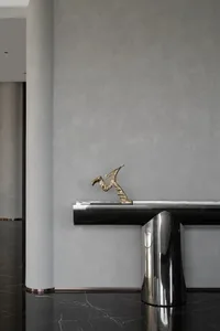A sleek, modern console table with a brass sculpture in a minimalist interior setting.