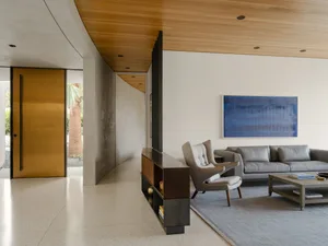Modern living room featuring concrete walls, a wooden ceiling, a gray sofa, and a blue abstract painting.