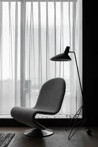 A modern living room featuring a fabric armchair and a minimalist floor lamp.