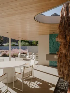 A modern minimalist outdoor lounge area with white furniture, concrete tiles, and wooden accents.
