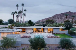 A modern residential house with concrete and glass materials featuring a pool and mountain view.
