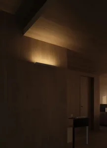 A modern light fixture mounted on a wooden wall casting warm, focused illumination.