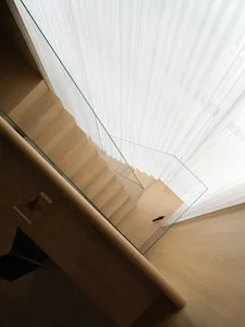 Modern minimalist stairs with wooden steps and glass railings.