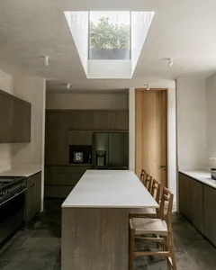 A modern residential kitchen featuring concrete countertops, wooden cabinets, and metallic appliances.