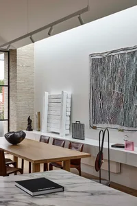 Modern dining room featuring wooden table, marble countertops, and concrete architectural elements.