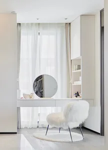 A modern dresser station featuring a circular mirror, white fur chair, and sleek design.
