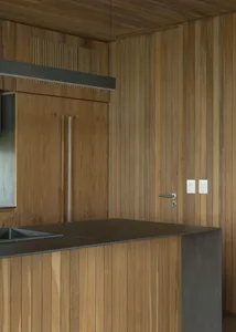 A modern kitchen with wooden walls and a stone countertop.