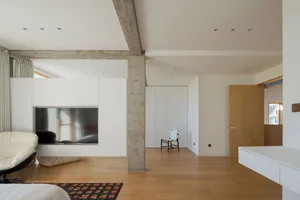 Modern living room with a concrete fireplace, white furniture, and a rug on wooden floor.