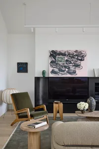 Modern living room featuring a green armchair, marble table, wood stool, and fabric ottoman.