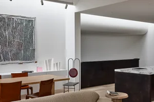 A modern minimalist dining room with wooden table, leather chairs, and marble accents.