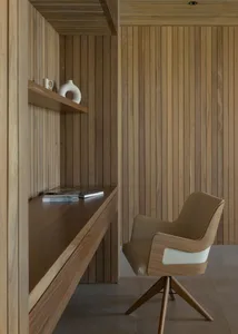 A modern minimalist home office with wooden elements, featuring a built-in desk and comfortable seating.