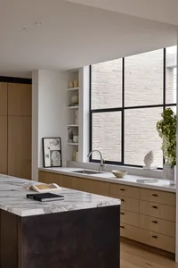 A modern residential kitchen featuring marble countertops and wooden cabinets.