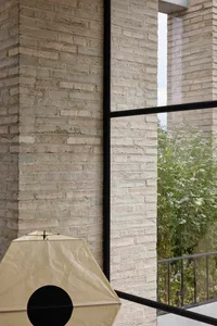 Modern interior with white brick walls and large windows looking out to greenery.