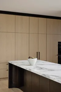A modern minimalist kitchen featuring a marble countertop with a bowl of fresh figs.