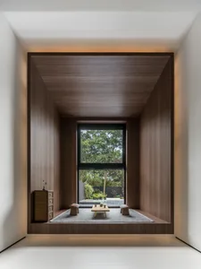 A minimalist living room with wooden walls, a small coffee table, and a large window showing a garden.