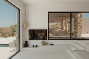 A minimalist residential interior with concrete flooring, glass walls, and a terrazzo dining area.
