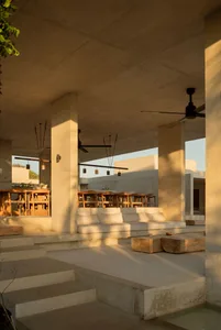 Minimalist rural hotel terrace with concrete columns, seating, and dining tables.
