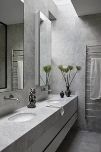 Modern minimalist bathroom with light grey ceramic tiles, grey floating vanity, and double sinks.