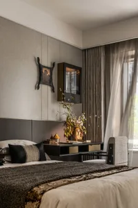 A modern bedroom featuring a bed with brown textiles, a side table with a vase of flowers, and a window with curtains.