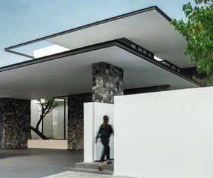 A modern building with a concrete and stone exterior, featuring large glass windows and a flat roof.