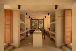 Modern kitchen with concrete walls and floor, minimalistic design, and open shelving.