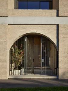 Modern entrance with an arched concrete gate and a glass door in the background.