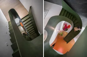 A modern interior design featuring a metallic staircase with green steps and a curved railing.