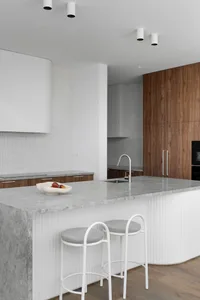 A modern kitchen featuring gray marble countertops and white cabinetry.