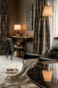 A modern living room with a black leather sofa, a cozy throw blanket, and a coffee table with a lamp.