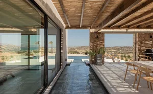 A modern residential exterior featuring concrete, glass, and stone materials.