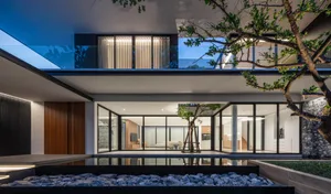 Modern residential interior with glass walls, wood flooring, and concrete patio.