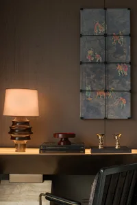 A modern study space featuring a wooden frame lamp on a sleek, dark desk with books, decorative objects, and a wooden artwork