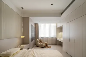 A minimalist bedroom with neutral tones, featuring a bed, a chair, and a window with curtains.