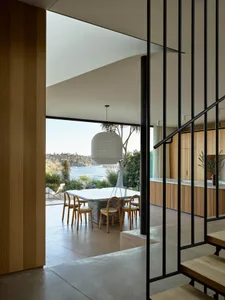 A modern interior design featuring glass windows, marble table, and wooden furniture.