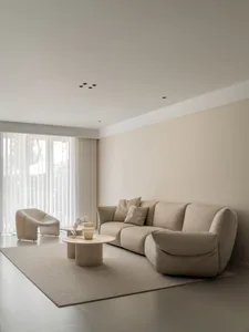 A minimalist living room with neutral colors, featuring a comfortable sofa, accent chair, and round coffee table.