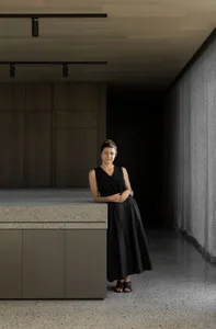 A woman standing in a modern office space with concrete flooring and minimalist decor.