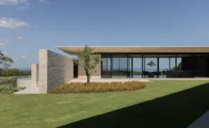 A modern house with glass walls, brick walls, and concrete patio.