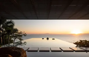 An infinity pool at sunset overlooking the sea with a modern architectural design.