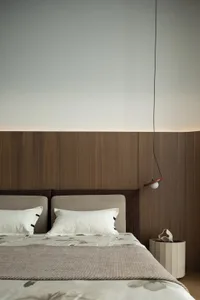 Minimalist bedroom featuring wooden panels and fabric bedding.