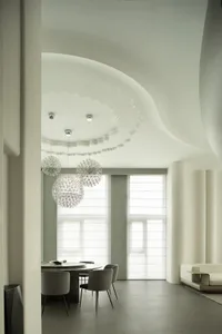 A minimalist dining room featuring textured concrete walls and ceiling.
