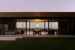 A minimalist house with a glass exterior and stone accents.