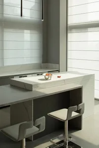 Minimalist kitchen design featuring a marble countertop and island with stainless steel stools.