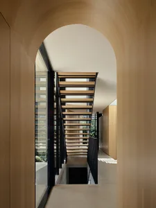 Architectural interior design featuring a modern wooden staircase with black railings and wooden flooring.